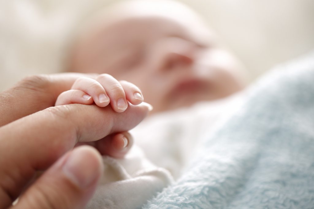 Sleeping baby clenches his parent's fingers